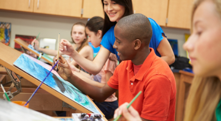 Male student and female teacher enjoy painting in a classroom 